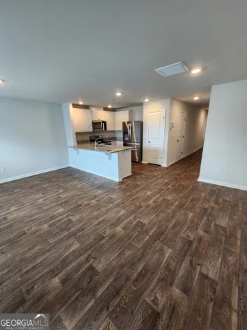 a view of kitchen and empty room with wooden floor