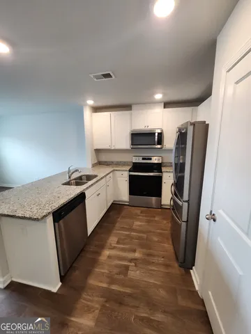 a large kitchen with stainless steel appliances granite countertop a stove a sink dishwasher a refrigerator and a stove with wooden floor