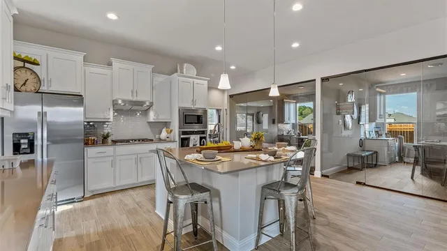a kitchen with stainless steel appliances a sink a stove a refrigerator cabinets and living room view