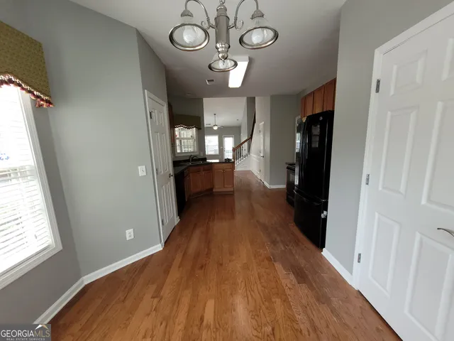 a view of a hallway with wooden floor and a kitchen