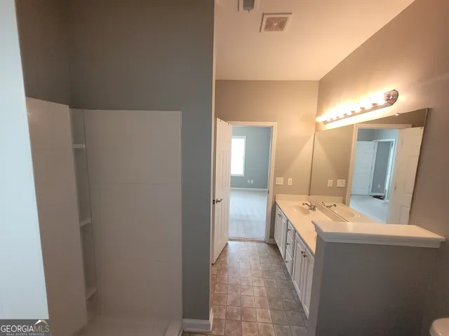 a large bathroom with a double vanity sink and mirror with shower