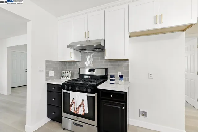 a kitchen with stainless steel appliances a stove a white cabinets and a refrigerator