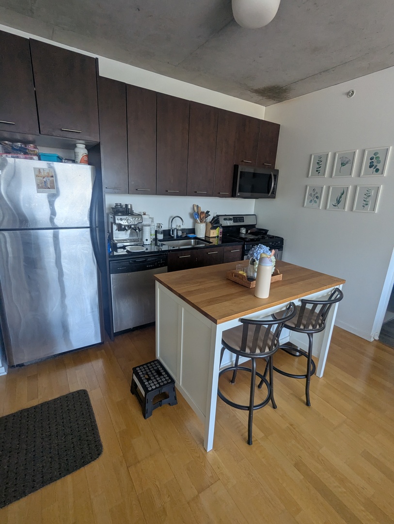659 West Randolph Street, Unit 711 Chicago, IL 60661 - Photo 5 of 14 a kitchen with a table chairs and a refrigerator