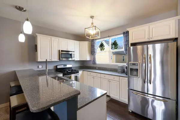 a kitchen with stainless steel appliances granite countertop a refrigerator a stove a sink dishwasher a dining table and chairs with wooden floor