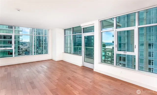 a view of an empty room with wooden floor and windows