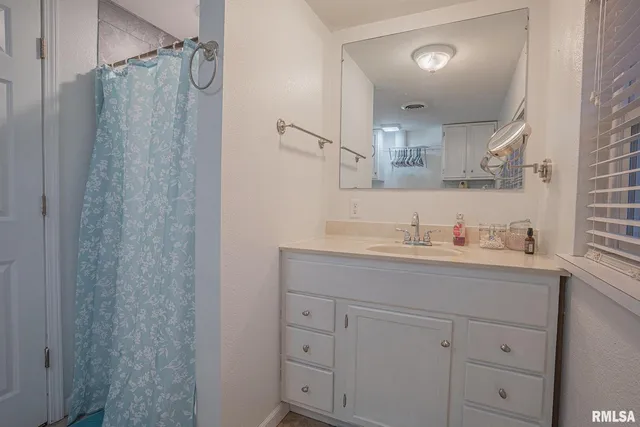 a bathroom with a granite countertop sink mirror and cabinets