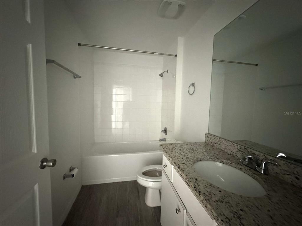 6386 East Rush Street Inverness, FL 34452 - Photo 15 of 21 a bathroom with a granite countertop sink a toilet a mirror and a tub