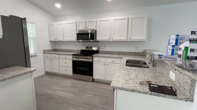 a kitchen with stainless steel appliances granite countertop a sink stove and refrigerator