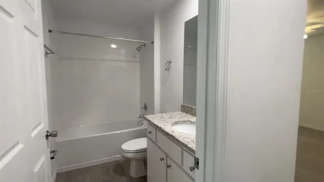 a bathroom with a granite countertop toilet a sink and a bathtub
