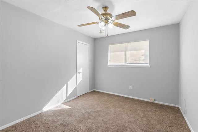 an empty room with a chandelier fan and windows