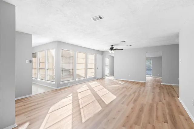 a view of an empty room with a window and wooden floor