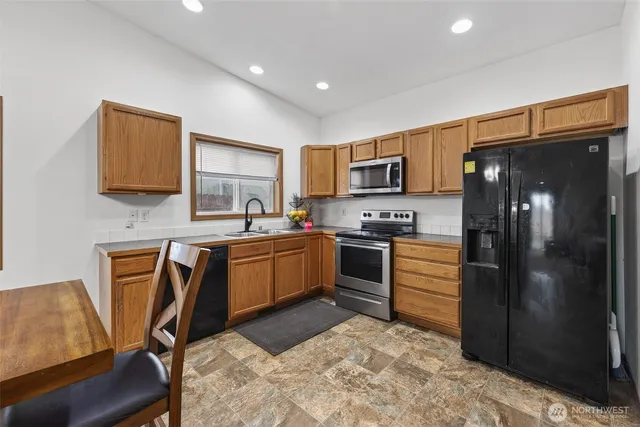 a kitchen with granite countertop a refrigerator stove top oven and sink