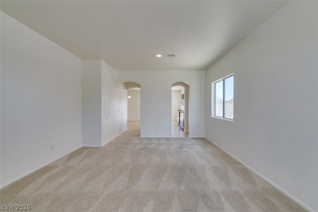 5150 Riverside Run Court North Las Vegas, NV 89081 - Photo 9 of 50 An inviting open-plan living space features neutral carpeting and bright natural light through a large window.