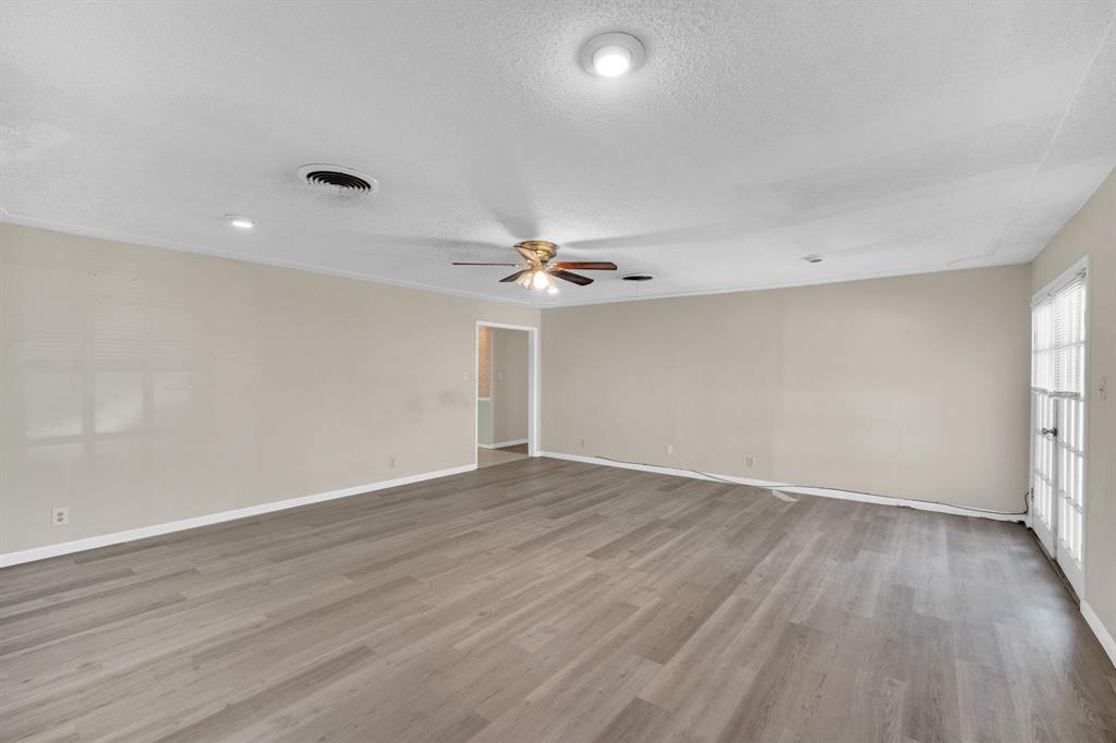 1320 Apache Street Arlington, TX 76012 - Photo 14 of 27 an empty room with wooden floor ceiling fan and windows