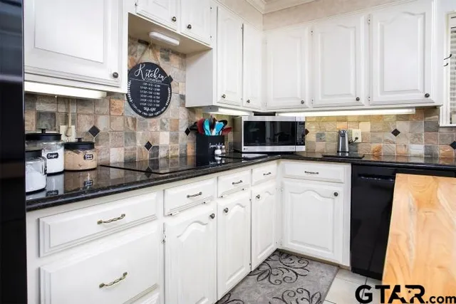 a kitchen with granite countertop white cabinets and stainless steel appliances