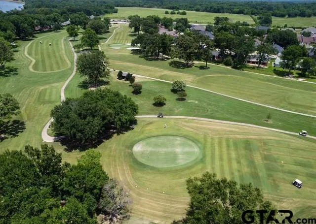 an aerial view of a residential houses with outdoor space and trees all around