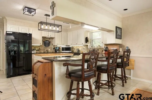 a dining hall with stainless steel appliances kitchen island granite countertop a table chairs and a refrigerator