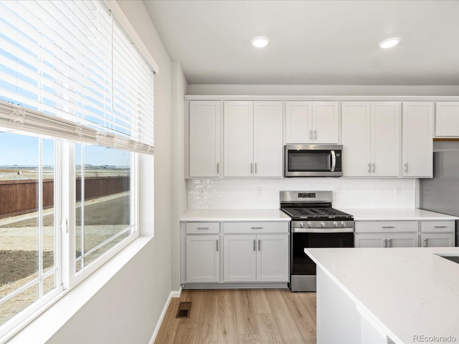 17517 East 89th Way Commerce City, CO 80022 - Photo 7 of 31 a kitchen with white cabinets and appliances