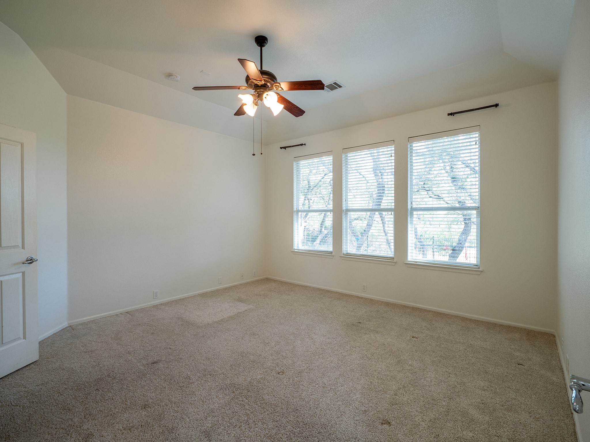 572 Big Meadow Road Austin, TX 78737 - Photo 14 of 32 A quiet retreat with a classic ceiling fan and three large windows overlooking lush trees.