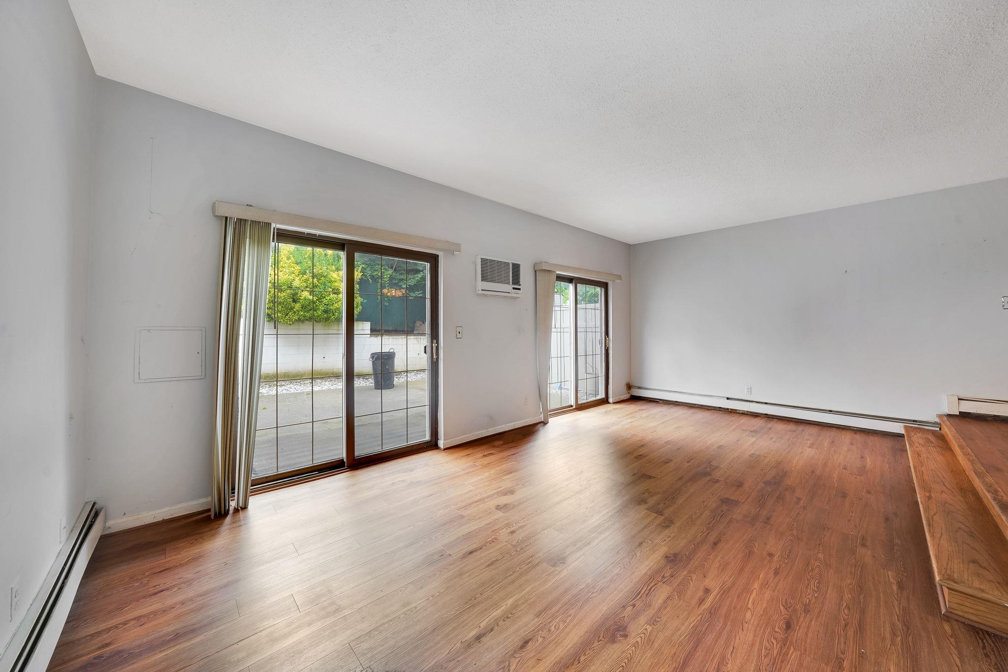 504 Julius Road, Unit 7C Queens, NY 11356 - Photo 11 of 22 an empty room with wooden floor and windows