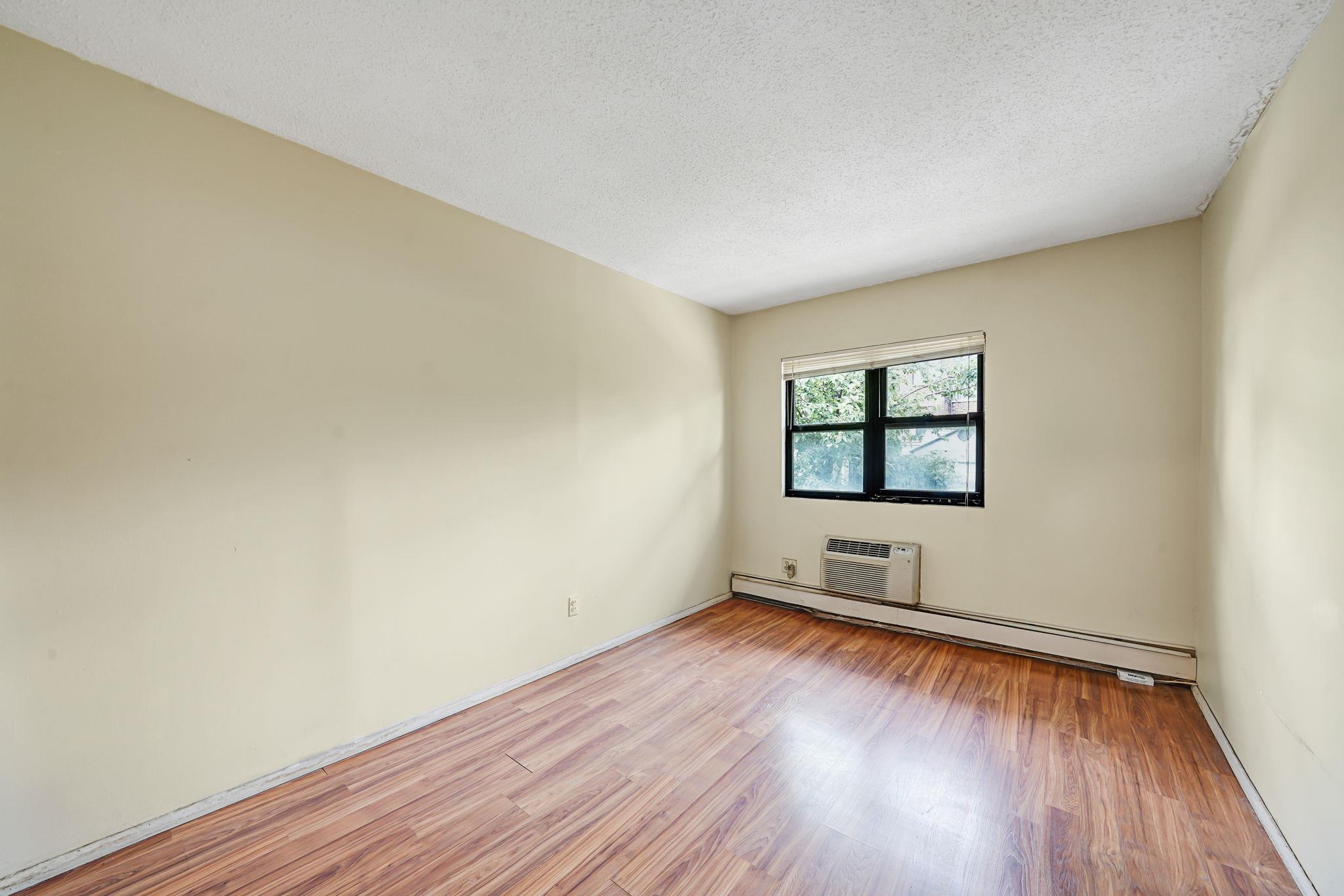 504 Julius Road, Unit 7C Queens, NY 11356 - Photo 14 of 22 an empty room with wooden floor and windows