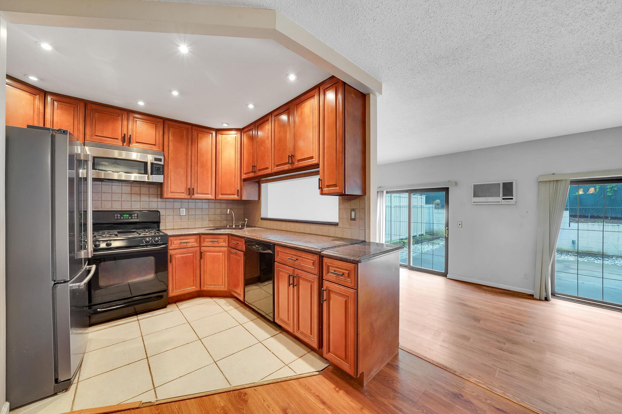 504 Julius Road, Unit 7C Queens, NY 11356 - Photo 4 of 22 a kitchen with stainless steel appliances granite countertop a refrigerator a sink dishwasher a stove with wooden cabinets and floor