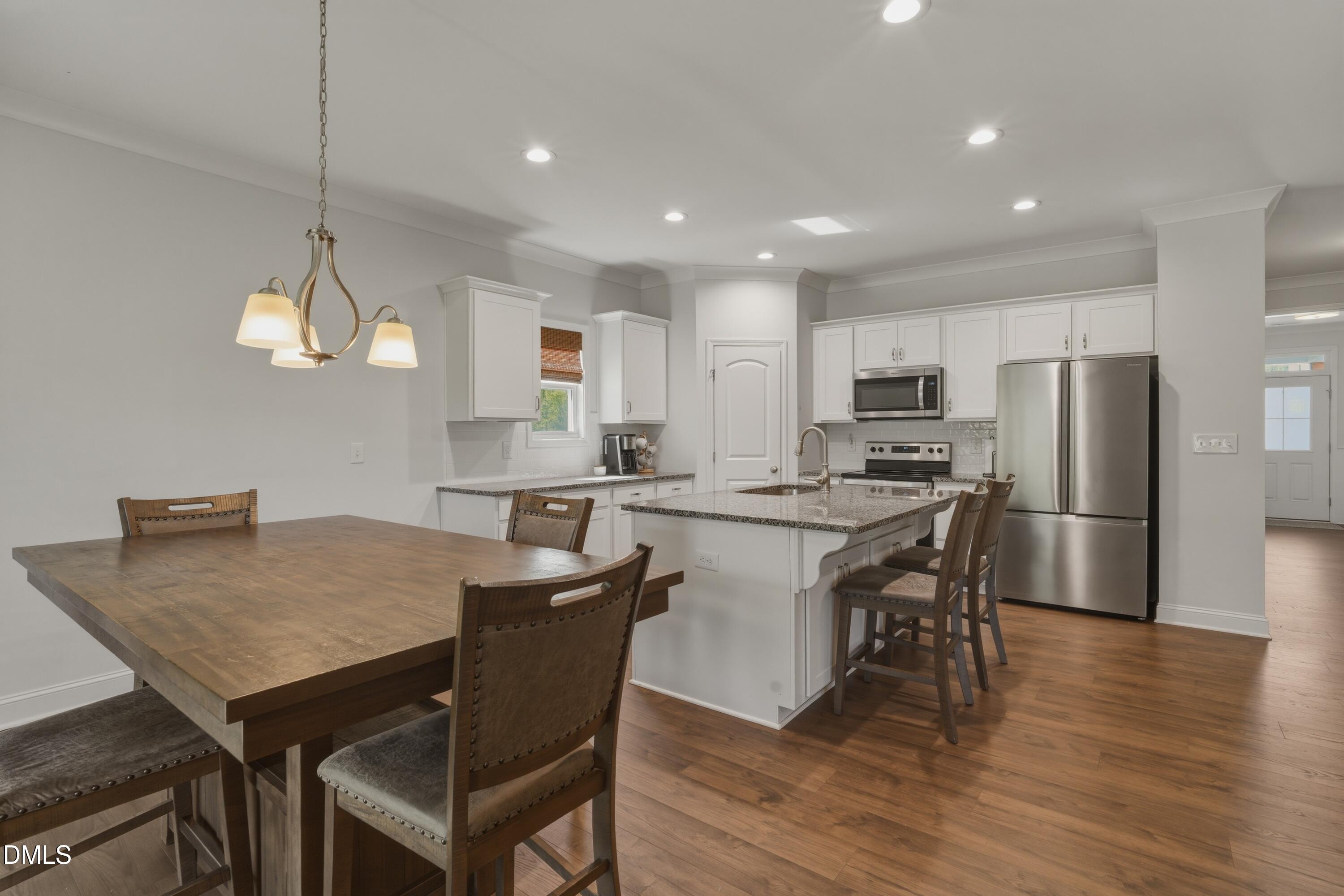 386 Howards Crossing Drive Wendell, NC 27591 - Photo 10 of 31 a kitchen with a dining table chairs refrigerator and cabinets