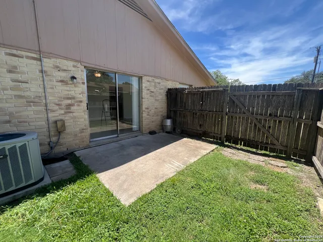 a view of a backyard with large trees and wooden fence