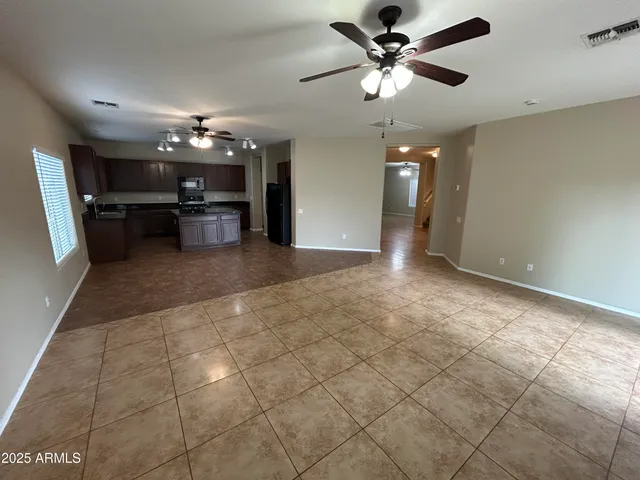 a view of a livingroom with a chandelier fan and kitchen view