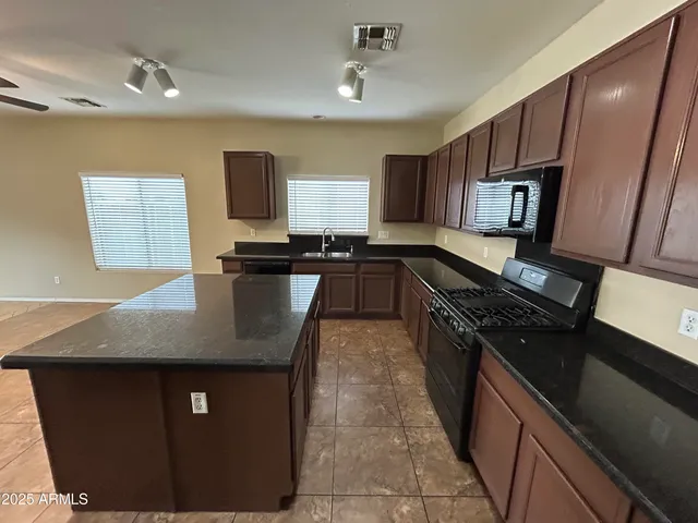 a kitchen with kitchen island granite countertop a sink stove and refrigerator