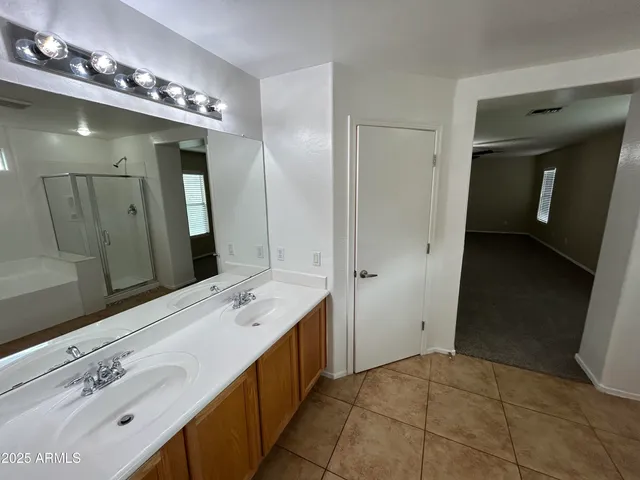 a spacious bathroom with a double vanity sink a mirror and shower