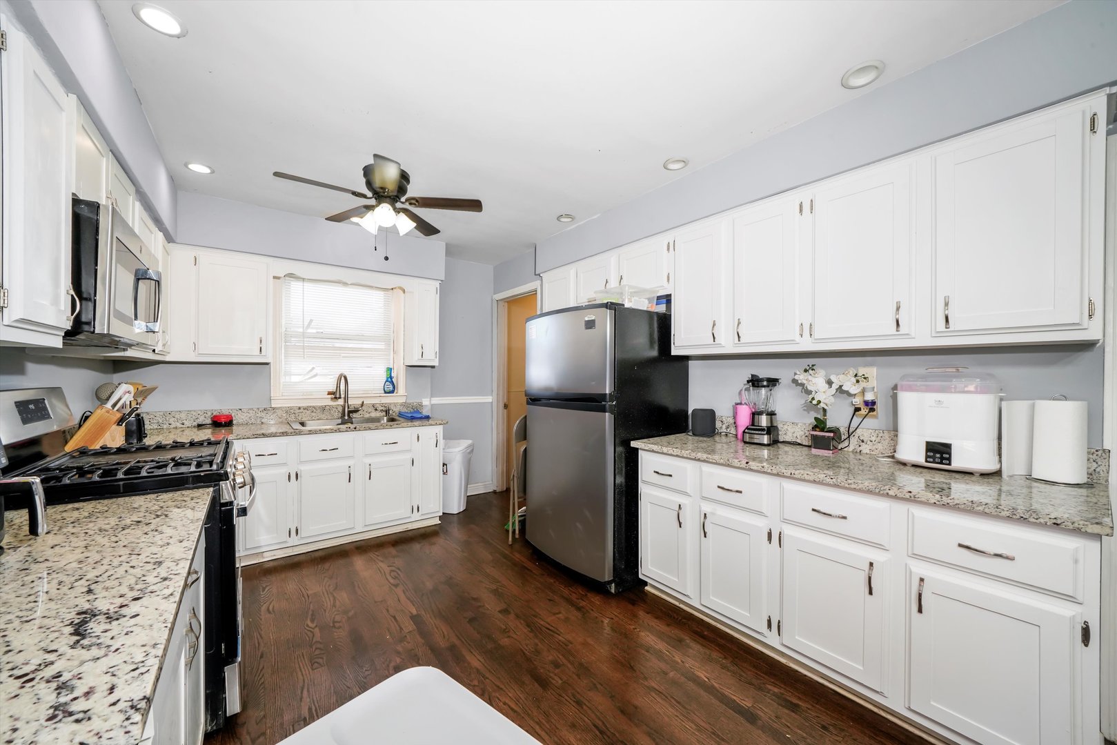 3705 West 65th Place Chicago, IL 60629 - Photo 13 of 31 a kitchen with a white cabinets and wooden floor