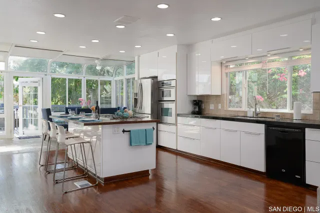 a kitchen with stainless steel appliances granite countertop sink window and white cabinets