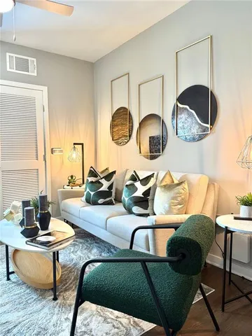 a living room with couches a mirror and a lamp next to a window with wooden floor
