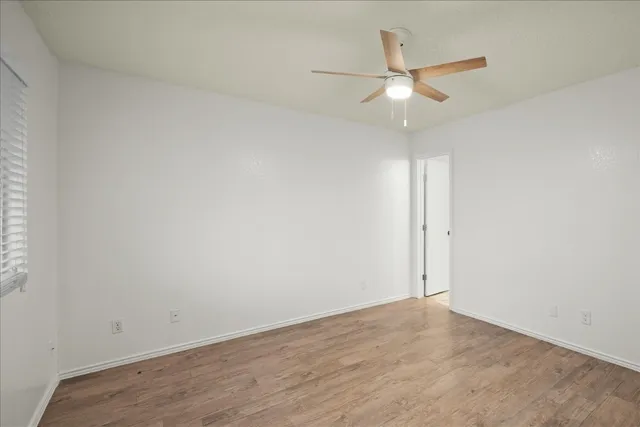 an empty room with a ceiling fan and wooden floor