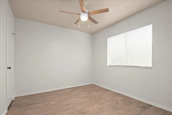 an empty room with a window and a fan