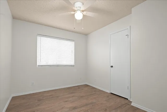 an empty room with a window and a fan