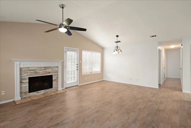 a view of an empty room with wooden floor fireplace and a window