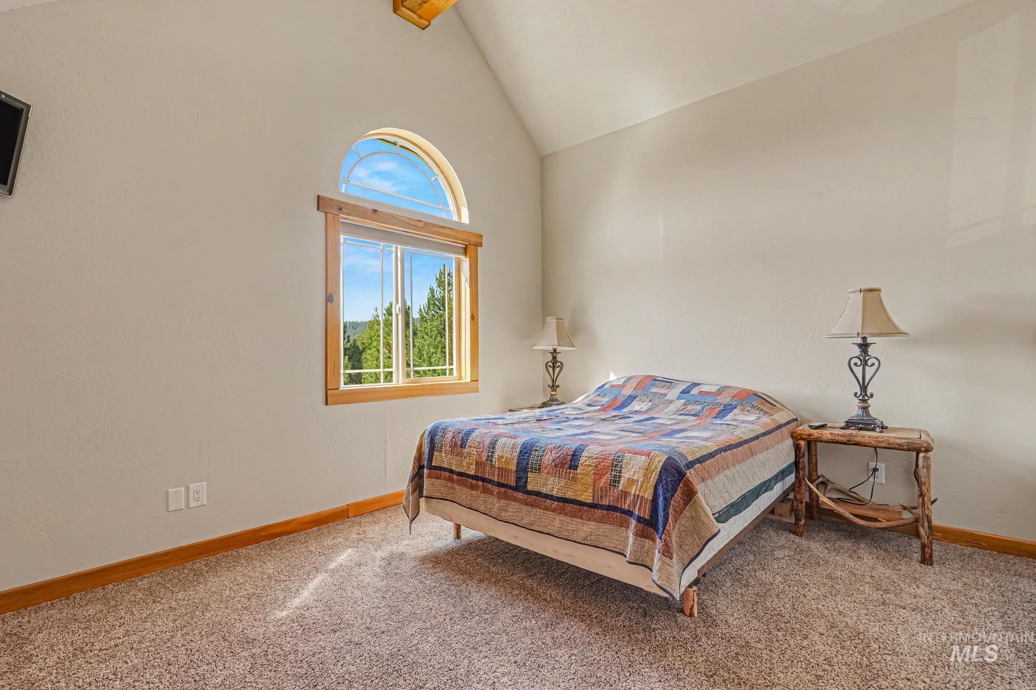 106 Wilderness Lake Road Cascade, ID 83611 - Photo 17 of 35 Vaulted ceiling with an arched window, wood-trim window frame, wall-to-wall carpeting, and wood baseboards