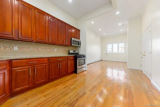 a kitchen with stainless steel appliances granite countertop wooden cabinets a sink and dishwasher with wooden floor