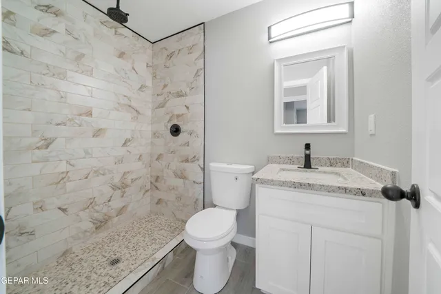a bathroom with a granite countertop sink toilet and shower