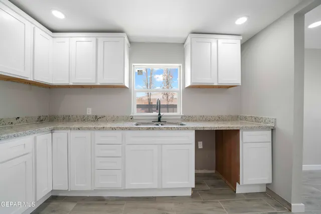 a kitchen with granite countertop a sink and cabinets