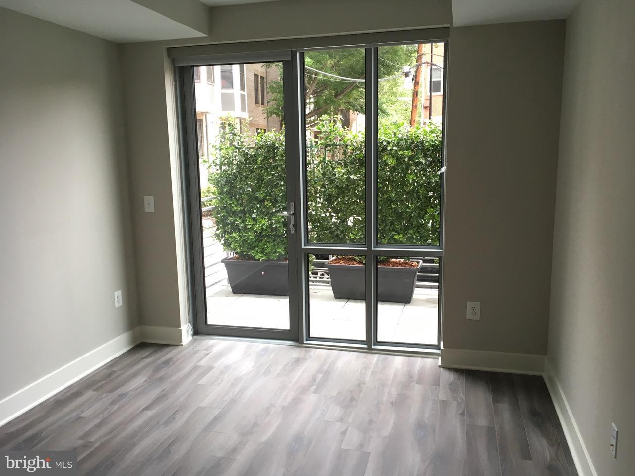 1311 13th Street Northwest, Unit 105 Washington, DC 20005 - Photo 3 of 15 a view of an empty room with wooden floor and a window