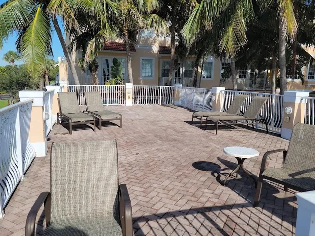 a view of a patio with table and chairs with wooden fence and large trees