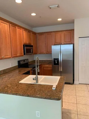 a kitchen with stainless steel appliances granite countertop a refrigerator a stove and a sink with wooden cabinets