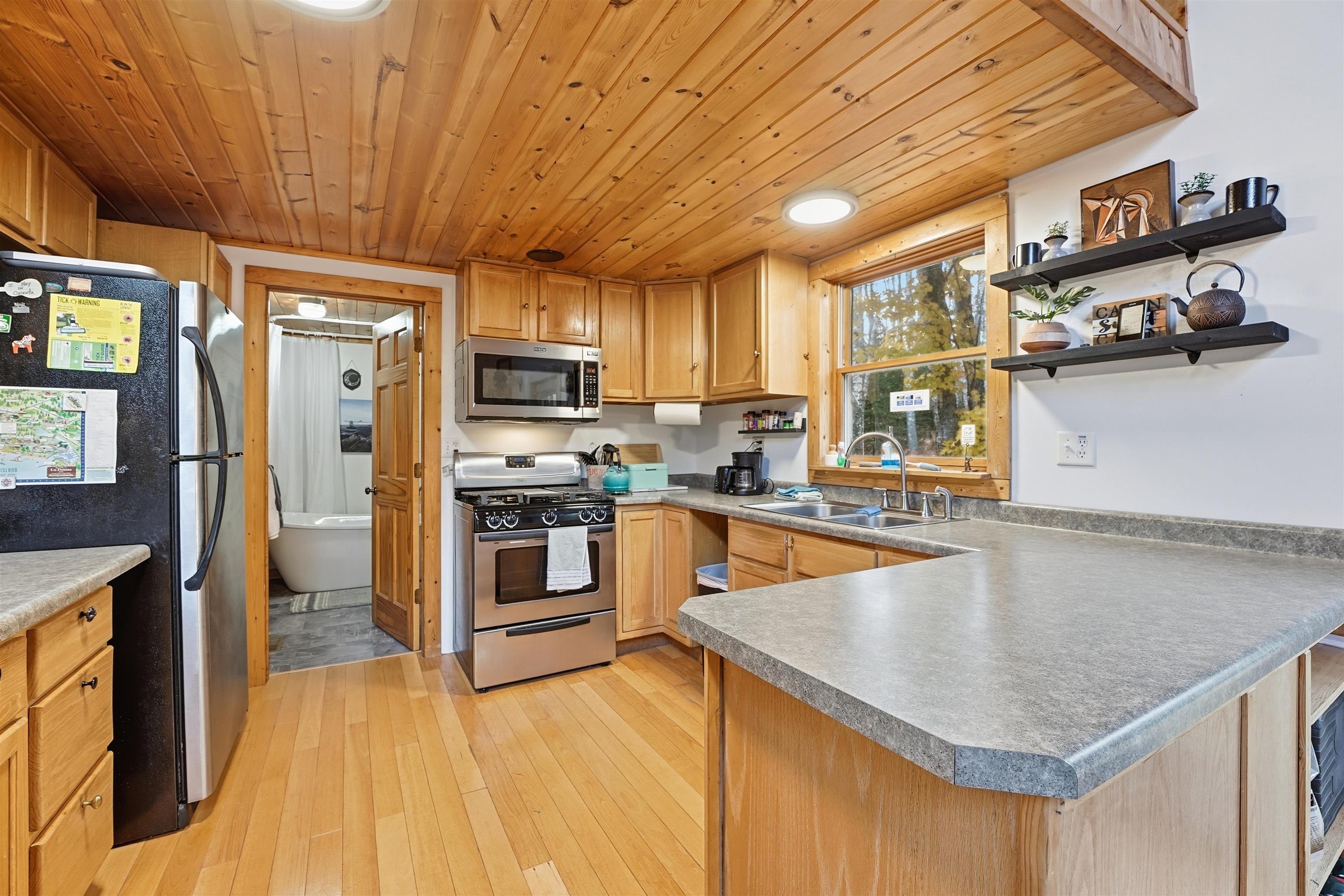 85255 Ravine Road Port Wing, WI 54865 - Photo 11 of 38 Kitchen with appliances with stainless steel finishes, a peninsula, wooden ceiling, light wood-style flooring, and open shelves