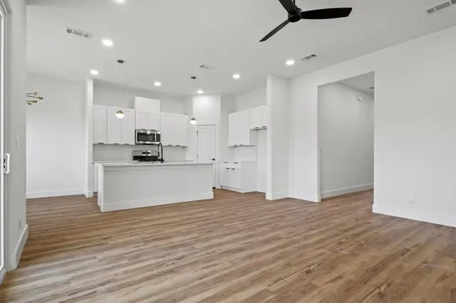 a view of kitchen with kitchen island wooden floor center island and stainless steel appliances
