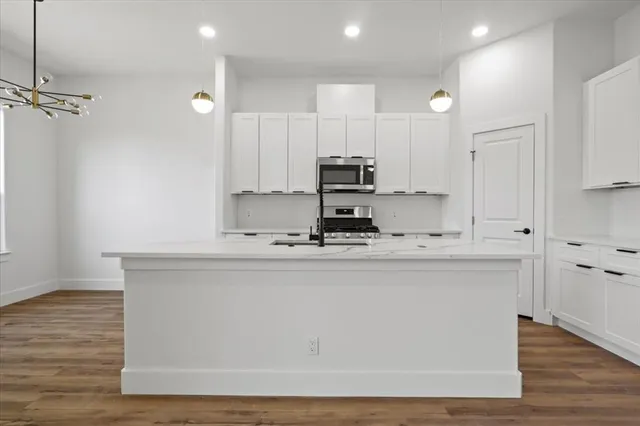 a kitchen with kitchen island white cabinets and stainless steel appliances