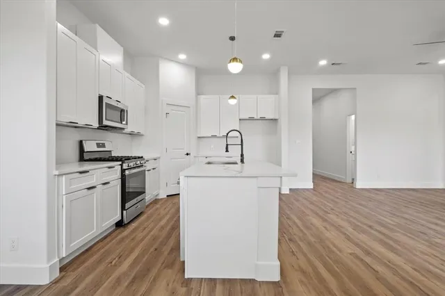 a kitchen with kitchen island white cabinets and stainless steel appliances
