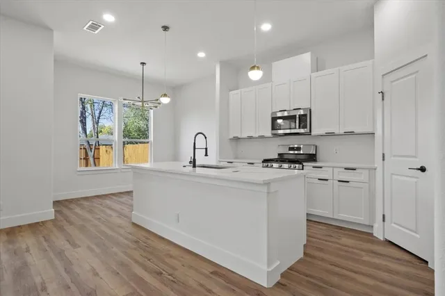 a kitchen with kitchen island granite countertop a sink cabinets and wooden floor